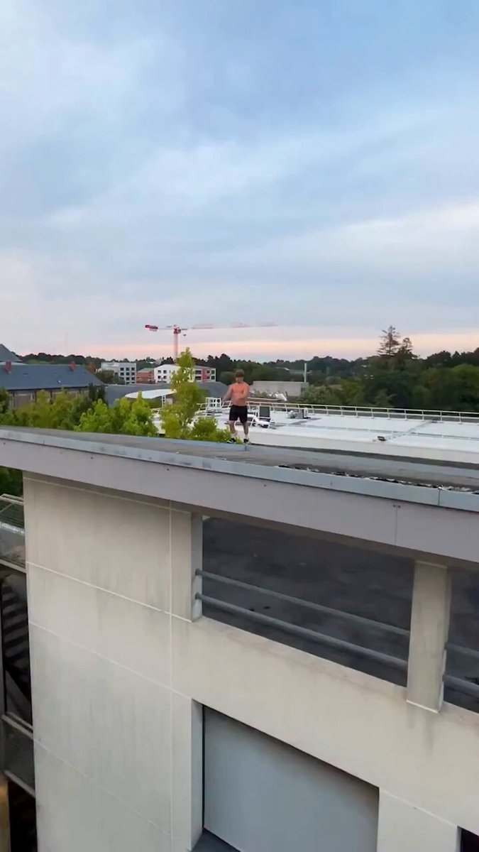 The image shows a man standing on top of a building, possibly a rooftop or balcony, with a view of the city below him. The surrounding area appears to be an urban environment, as there are several buildings visible in the background. The photo also contains text that reads "We turn power into Bitcoin. DM us to get started. #BitcoinMining #Crypto #Mining". This message seems to be related to Bitcoin mining or cryptocurrency, possibly suggesting a connection between the man's location and the world of digital currency.