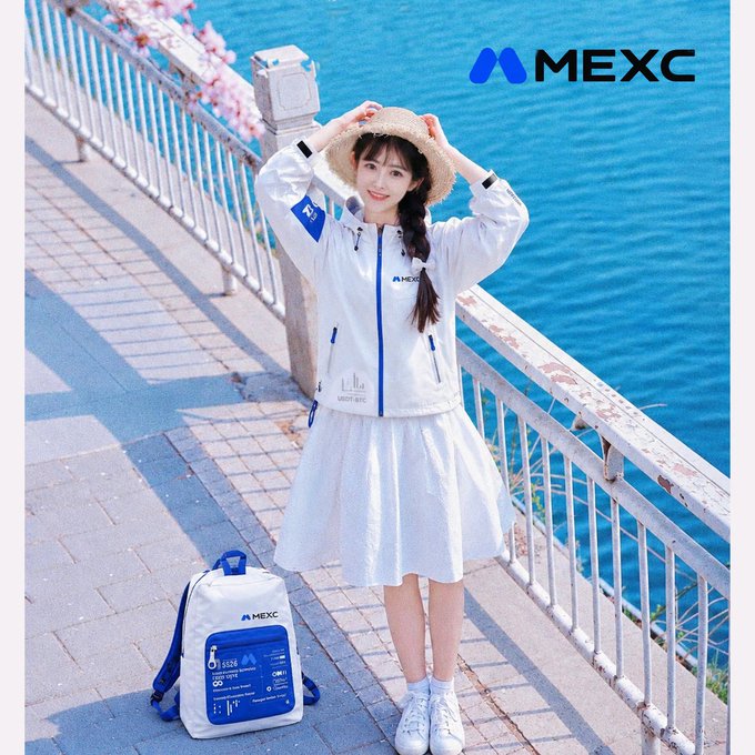 An advertisement for MEXC features a young woman in a white jacket, white skirt, and straw hat posing by the water with a matching MEXC backpack beside her.