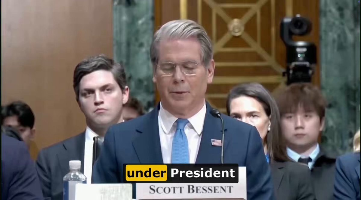The image shows a man giving a speech at a press conference, with a crowd of people watching him. The text "under President Scott Bessent" appears multiple times throughout the scene, suggesting that this event is related to the U.S. Treasury Secretary's position or role in the country. The post also mentions Bitcoin and its potential future impact on the economy, which could be related to the speech given by the Treasury Secretary.