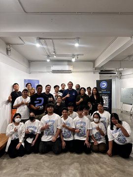 The image shows a group of people posing together, wearing matching shirts with the word "Dash" printed on them. The group consists of both men and women, all dressed in white t-shirts that have the word "Dash" written on them. They are standing close to each other, forming a circle or a semi-circle, which is typical for a group photo. In the background, there's an air conditioning unit mounted on the wall, indicating that they might be indoors at a venue with temperature control. The image also contains text that reads "Dash Thailand Meetup #2 was a memorable gathering of the Dash community in Thailand."