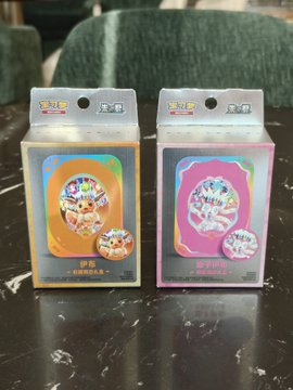 Two Pokémon Trading Card Game Eevee Evolution booster boxes—one orange (Series A "Eevee Heroes") and one pink (Series B "Eevee Heroes")—sit on a dark marble surface, likely the consolation "slice of cake" prize mentioned after a rough 23U-to-1U pull disappointment.
