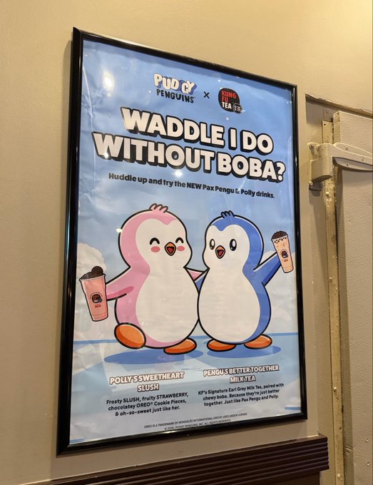 A framed advertisement poster for a 'Pudu & Penguins x Gong Cha' collaboration featuring two cartoon penguins holding boba drinks, with the headline 'WADDLE I DO WITHOUT BOBA?' promoting new Pengu & Polly drinks like 'Polly's Sweetheart Slush' and 'Pengu's Better Together Milk Tea'.