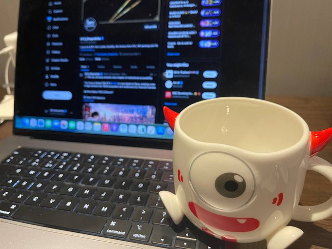 A MacBook displays crypto content with visible "TRON" text alongside a cute white TRON Bull mug with red horns sitting on the keyboard, perfectly matching the late-night work setup for creating crypto content.