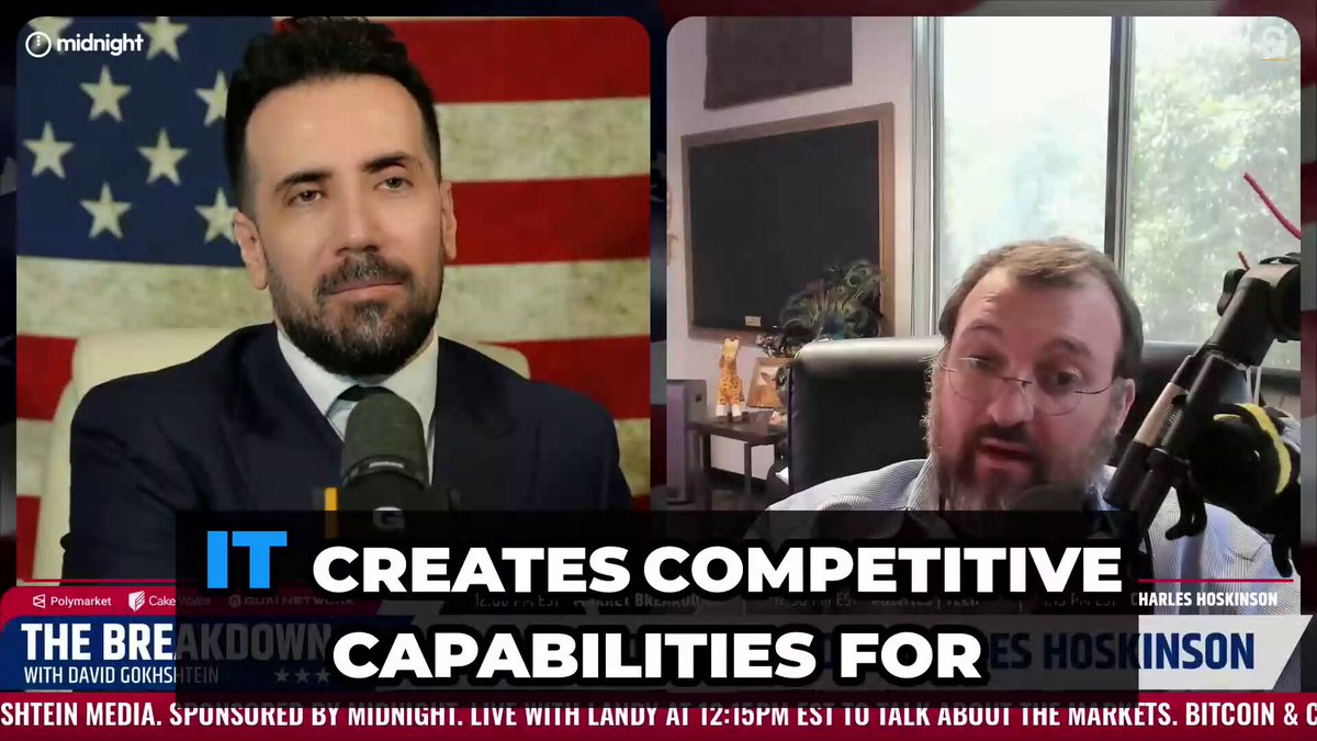 The image features two men sitting at a desk with microphones, appearing to be discussing something related to cryptocurrency or blockchain technology. The background of the image includes an American flag, which suggests that they might be having this conversation during a political event or discussion about the impact of cryptocurrencies on the economy and financial systems.