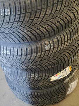 A close-up of three stacked new Firestone tires with visible tread patterns and product label stickers still attached.