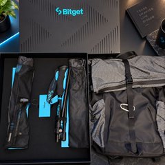 A promotional image for "Bitget" displaying a laptop sleeve and a backpack in dark gray and light gray colors, alongside the brand's logo and other accessories.