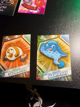 A photograph of Pokémon trading cards featuring Clownfish and Manta Ray on the table.