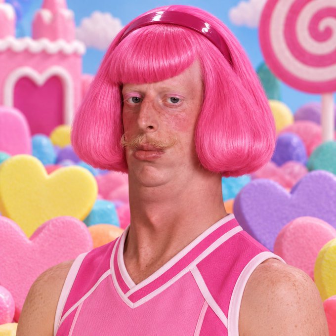 A digitally edited image showing a man with a pink mustache wearing a bright pink bob wig with bangs and a matching pink athletic tank top, set against a vibrant candy-themed background with lollipops and hearts.