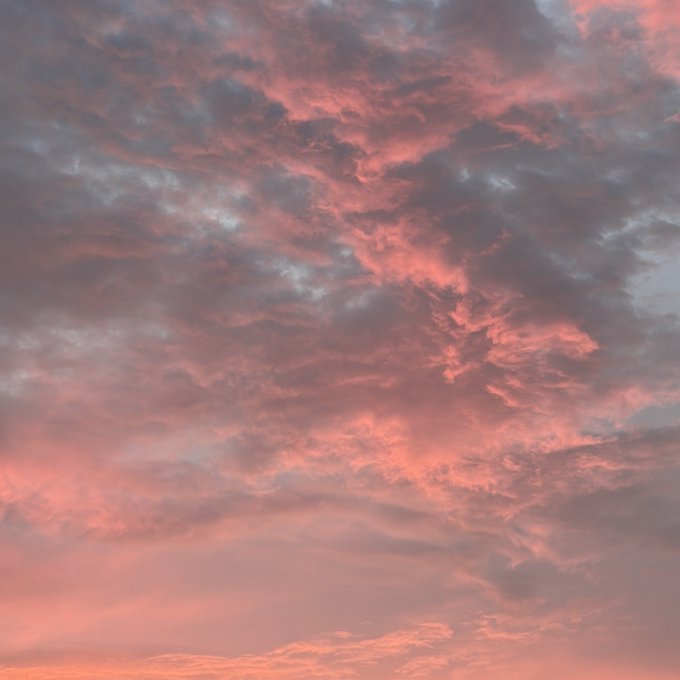 A vibrant sunset sky filled with textured clouds in shades of pink, orange, and blue.