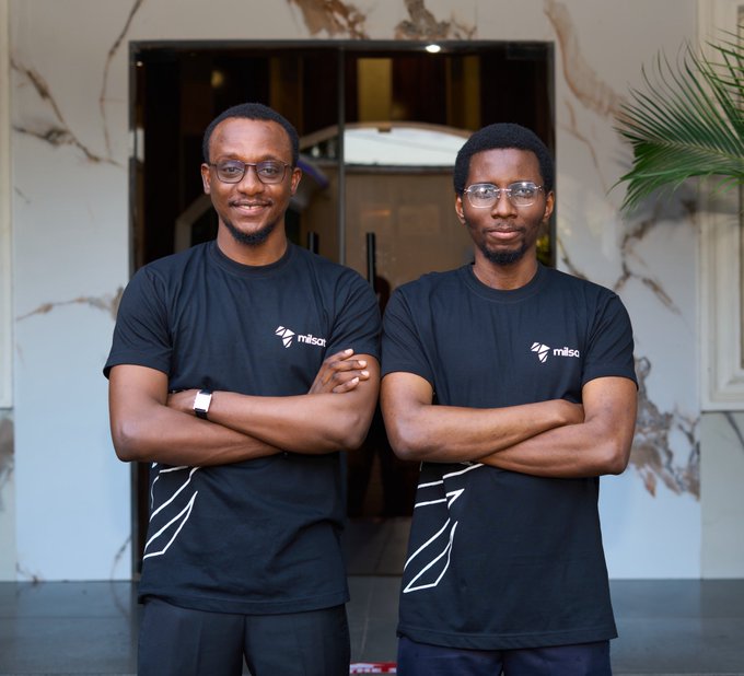 Two men wearing matching black t-shirts with the 'misc' logo stand with their arms crossed in front of a building.