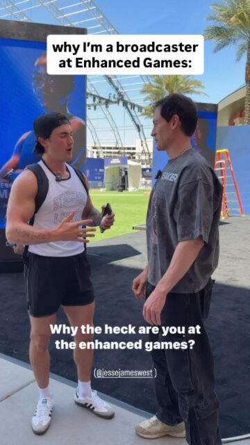 The image shows two men standing next to each other, engaged in a conversation. One man has his arms crossed over his chest while the other stands with his hands at his sides. The background features an advertisement for Enhanced Games, suggesting that they are discussing or reviewing video games.