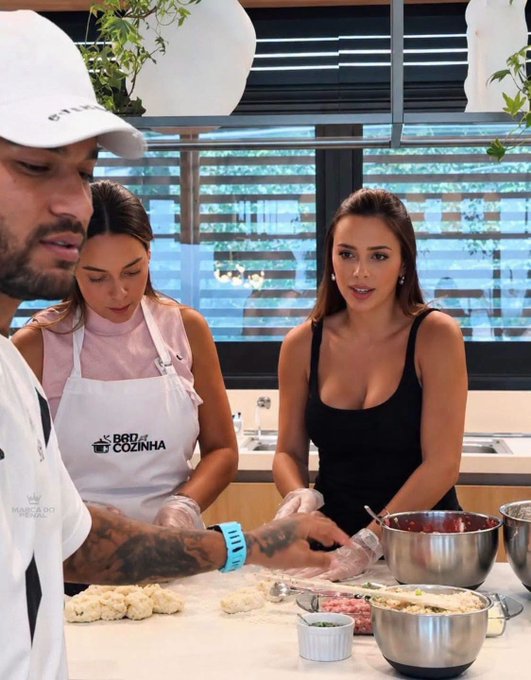 Three people are in a kitchen cooking scene, with one person wearing an apron labeled 'PROF de COZINHA' as they prepare food together.