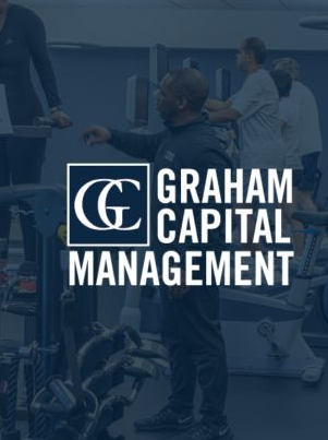 A faded image shows what appears to be a trading floor or financial office setting with people working at desks, overlaid with the prominent "GRAHAM CAPITAL MANAGEMENT" logo in white text. The image visually anchors the news about Graham Capital Management selling off 75% of its Bitcoin ETF holdings in Q2, now retaining $9M in BlackRock's IBIT BTC ETF.