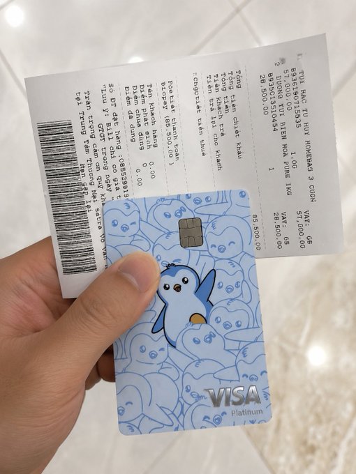 The image shows a person's hand holding a Visa Mastercard, which has a penguin design on it. The person is also holding a receipt for their purchase at a store or restaurant. The post about stablecoins mentions that they are useful but can be used in real-world scenarios like making purchases using the KAST card. This image captures a moment where someone is using their Mastercard to make a payment, demonstrating how stablecoins can be utilized in everyday situations beyond just digital currency exchanges.
