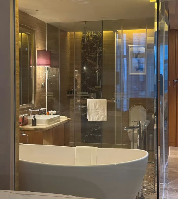Luxury hotel bathroom featuring a freestanding white bathtub, glass shower enclosure, and warm wooden finishes, identified as Grand Nikko Tokyo Daiba.
