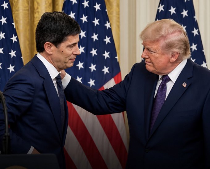 Two men in dark suits—one with dark hair and the other with distinctive blonde hair wearing an American flag lapel pin—stand facing each other in front of multiple American flags, with the blonde-haired man placing his hand on the other man's shoulder in what appears to be a formal White House setting.

The image appears unrelated to the accompanying post about upcoming economic indicators and Federal Reserve interest rate decisions, as it depicts what looks like a political or ceremonial moment rather than any financial or monetary policy event.