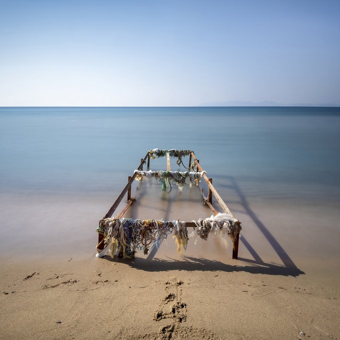 The image features a wooden pier with various objects attached to it, including a bunch of clothes that are hanging from it. The pier appears to be abandoned or neglected, as there is no one around it. The beach setting suggests that this scene might have taken place during the day when people would typically visit and enjoy the shoreline activities. The image seems to be related to the post "Unchained Horizon" by Love Pelin, which could possibly be a description of an abandoned pier or a similar location.