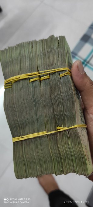 A hand holds a bundle of dried green leaves tied with yellow string, photographed with a Redmi Note 5 Pro on March 28, 2022.