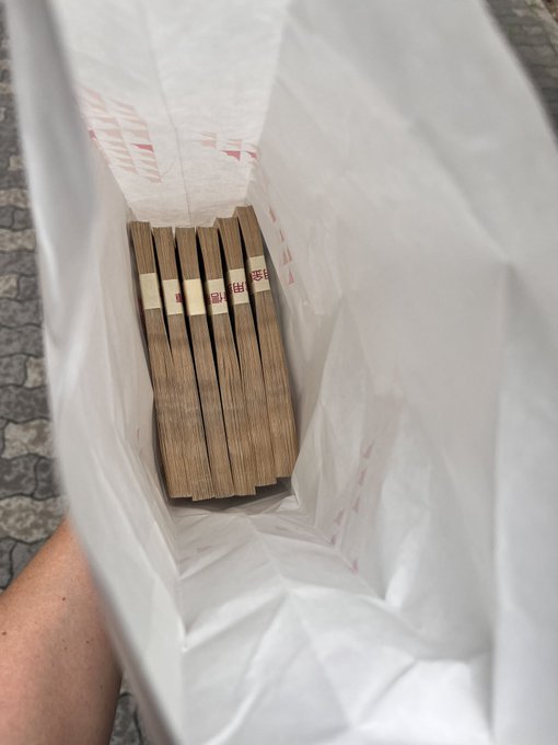 A hand holds open a white shopping bag revealing a stack of wooden blocks labeled "Ripple," referencing the crypto's ticker XRP, with the post contemplating whether to buy more XRP.