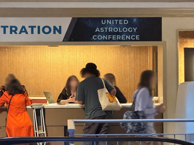 People gather at a registration desk under a banner reading "UNITED ASTROLOGY CONFERENCE," with one attendee carrying a tote bag featuring the "FLOCK" logo, highlighting the brand's presence at the event.