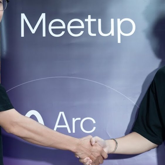 Two people shake hands in front of a purple banner displaying the text 'Meetup' and 'Arc'.