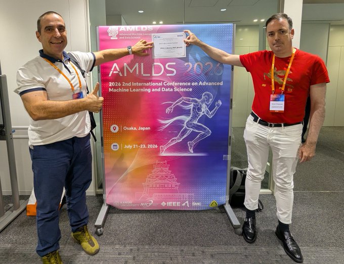 Two men pose cheerfully on either side of a conference banner for 'AMLDS 2026 - 2026 2nd International Conference on Advanced Machine Learning and Data Science' taking place July 21-23, 2026, in Osaka, Japan.
