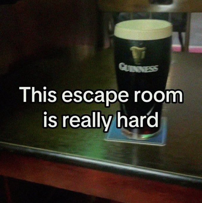 A dark photo of a pint of Guinness beer on a bar counter with overlay text reading "This escape room is really hard".
