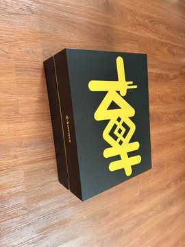 A black gift box with yellow Chinese calligraphy reading "九周年" (9th anniversary) sits on a wooden surface, representing the Binance 9th anniversary gift box mentioned in the post thanking Binance for the commemorative package.