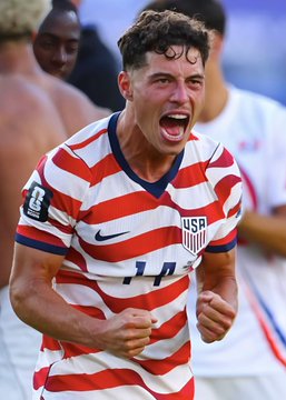 A young soccer player wearing the United States national team jersey, number 14, pumps his fists and shouts in celebration—visually capturing the kind of victory the bettor is betting on with a $35,000 wager on the USMNT to beat Chile.