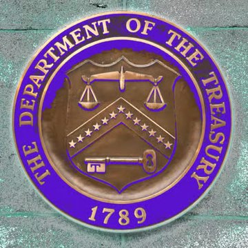 The seal of the U.S. Department of the Treasury, established in 1789, is shown in bronze and blue. The seal features the iconic imagery of a balance scale, chevron with stars, and a key, symbolizing justice, authority, and the Treasury's role in enforcing financial sanctions—relevant to its recent action targeting Iranian crypto exchange BitBank for allegedly facilitating bitcoin transfers to the IRGC.