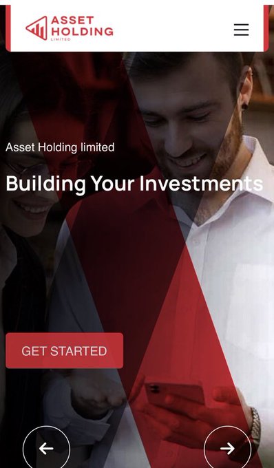 The image shows a website for an asset holding company called Assetholdltd.com (possibly Bitcoin Cash). The website has a red background with white text, which reads "Building Your Investments" at the top of the page. Below this, there is a photo of two people looking at their phones and smiling. The main content of the image is a man holding his phone in front of him while another person looks on.
