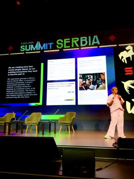 A speaker stands on stage presenting slides at the "SUMMIT SERBIA," displaying text about Solana's community-building and the SHEFI program, aligning with the post's enthusiasm for bringing the event's in-person Solana networking energy to London.