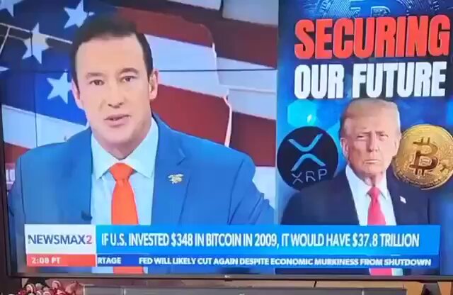The image shows a news broadcast featuring two men, one wearing a blue suit and red tie talking about Bitcoin and its potential use as a means of paying off national debt. The other man is wearing a gold suit and tie, which could be an indication that he is a political figure or a high-ranking government official.

The news program discusses the idea of using Bitcoin to pay off national debt, suggesting that it might be a viable solution for the country's financial issues. This concept has been widely discussed on various platforms, including social media and news channels like Newsmax. The image captures this moment in time when the topic is being debated by experts and the public alike.