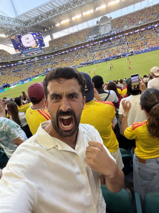 A passionate fan screams in excitement while watching a soccer match in a packed stadium, with crowds in yellow jerseys surrounding him. The image reflects the post's sentiment of risky betting, mirroring the gambler's thrill of wagering on Colombia to recover losses from $MSTR.