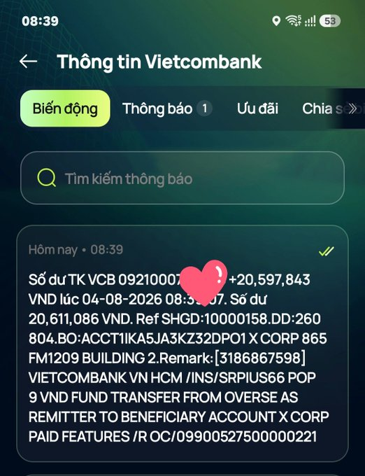 A Vietnamese banking app notification from Vietcombank showing a transaction credit of +20,597,843 VND dated 04-08-2026, with the partial account number obscured by a heart emoji, describing a VND fund transfer from overseas remitter to X Corp.