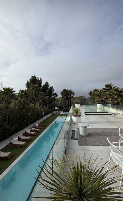 A sleek rooftop pool terrace with palm trees, lounge chairs, and modern outdoor seating under a cloudy sky. The post invites followers to grab a coffee from Sweetflips and share their Solana (SOL) wallet address in the comments.
