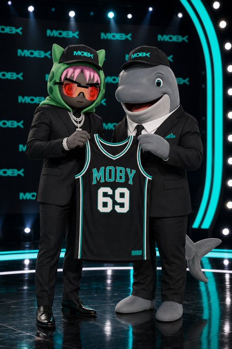 Two mascots — a cat-like figure with pink hair and sunglasses, and a shark wearing suits — hold up a black "MOBY 69" jersey on a teal-lit stage branded with the "MOBX" logo, tying into the promotional post's pitch for Moby's trading agent platform.
