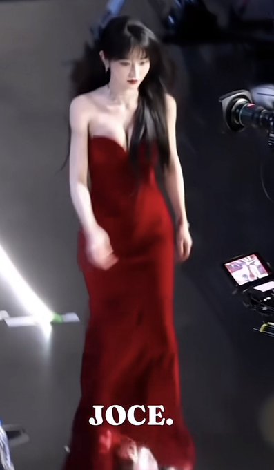 A woman in an elegant, flowing red strapless gown walking on a runway, with the text 'JOCE.' displayed at the bottom.