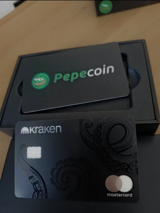 A black 'Pepecoin' branded card in a box next to a black Kraken Mastercard featuring octopus tentacle designs.