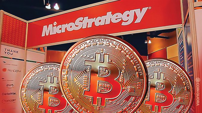 The image shows an exhibit at a business convention center featuring several large Bitcoins displayed behind a red sign that says "MicroStrategy". The coins are encased in a metal frame, giving them a shiny appearance. The phrase "strategy moves $30.3M" is also visible, possibly referring to the worth of these Bitcoins or other market-related matters. The scene seems to be focused on promoting Cryptocurrency and its strategies.