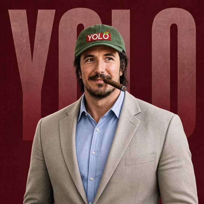 A promotional image of a man wearing a green cap with a 'YOLO' logo, a tan blazer over a blue shirt, smoking a cigar against a dark red 'YOLO' branded background.
