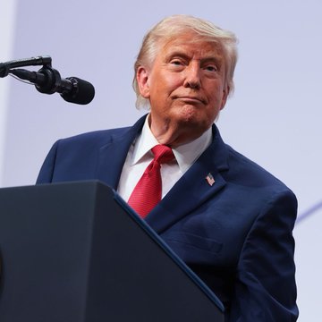 Donald Trump stands at a podium delivering a speech, aligning with his statement that the US is leading in AI and crypto.