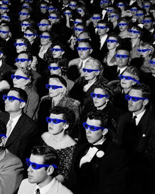 A black-and-white vintage photo of a theater audience in formal attire, edited so that everyone is wearing bright blue 3D-style glasses.