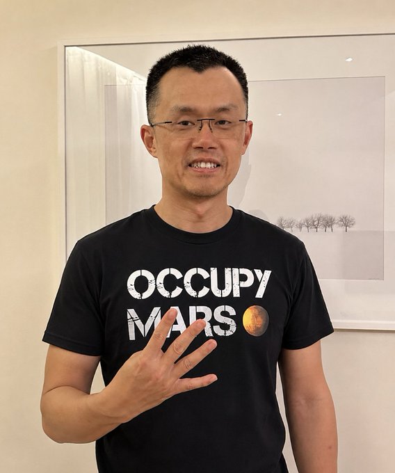 In the image, a man wearing a black t-shirt with white text that says "Occupy Mars" is standing in front of a gray wall. The image also includes some text about space exploration and SpaceX launching a new space station. There is no visible content or objects like an elbow or a finger. This image seems to be related to the post about occupying Mars, expressing support for the idea through a symbolic gesture using the letters on the man's shirt.