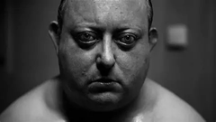 A bald, shirtless man with a somber expression stares directly at the camera in a stark black-and-white close-up portrait. The image accompanies a post addressing Jack Duvall (likely Jack Doohan), welcoming him to the $MEMIPEDE community with a message of support and solidarity.