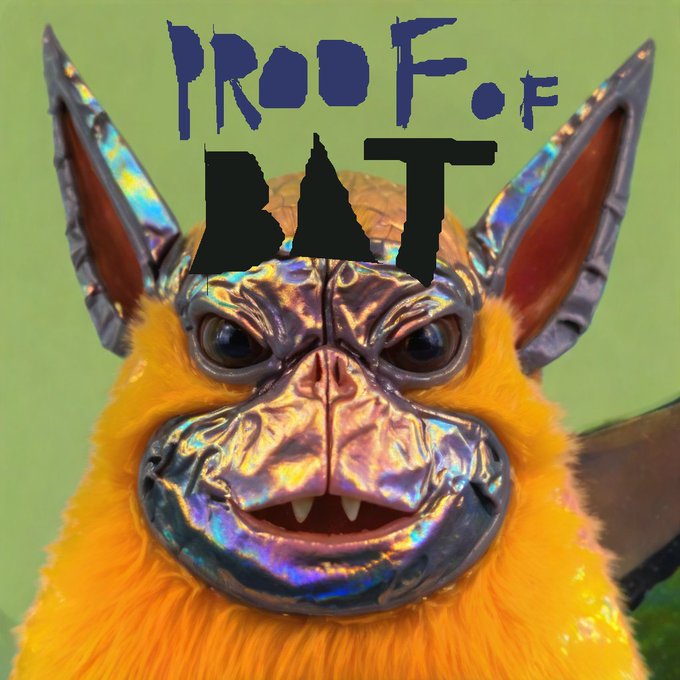 A close-up image of a bat-like creature with orange fur and an iridescent metallic silver face, with the text 'PROOF OF BAT' displayed in stylized blue and black lettering at the top against a green background.