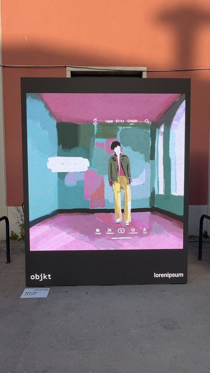 The image features a large, colorful painting of a man standing inside an art gallery or museum. The painting depicts the man wearing a green jacket and yellow pants, with his back facing the viewer. The background of the painting is pink and blue, creating a vibrant atmosphere. The painting is displayed on a black frame, which contrasts with the bright colors of the artwork.

The image also includes text that reads "I couldn't go to Lisbon, but happy that my art was there. Big thanks to @kikanicolela and @objktone for making it possible! and now 'Traptrap' belongs to dear @iamcfw". This message is written in a smaller font size than the rest of the image, drawing attention to the painting itself.