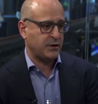 A man in a dark suit and glasses speaks, appearing to be from a BlackRock interview, providing visual context for the post about BlackRock's Bitcoin ETF architect warning that Asia could overtake the U.S. in crypto regulation, highlighting the competitive race between Japan's advancing crypto framework and the U.S. waiting on the CLARITY Act.