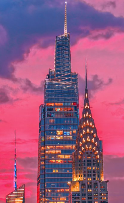 The Chrysler Building and a modern skyscraper stand illuminated against a vibrant pink and purple sunset sky.