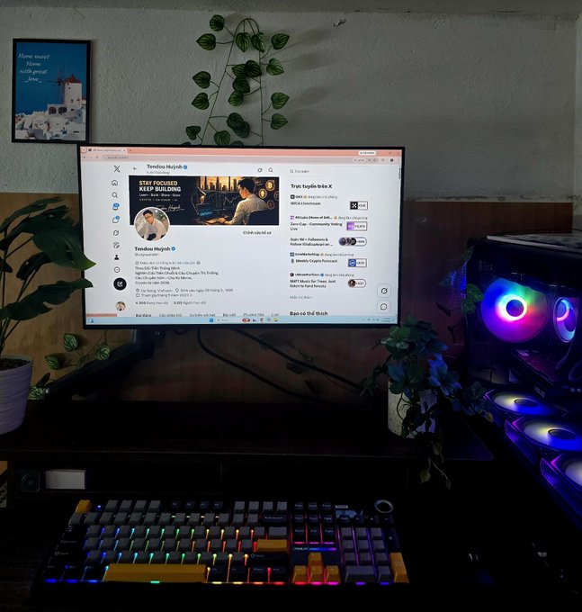 A computer setup with an RGB keyboard, a PC with glowing fans, and a monitor displaying the X (Twitter) profile of 'Tendoo Huỳnh' with a banner reading 'STAY FOCUSED KEEP BUILDING'.